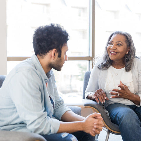 Two people sitting in a modern office setting, engaged in conversation.