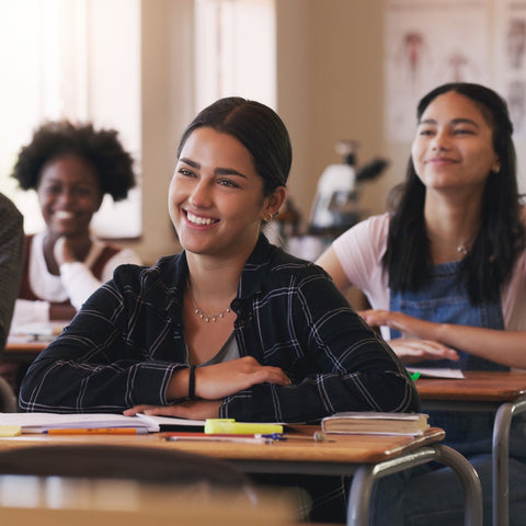 Classroom setting with students sitting at desks, smiling.