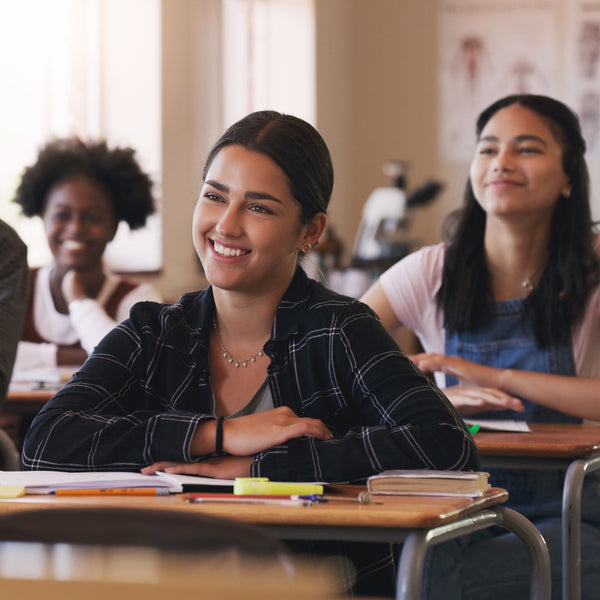 Classroom setting with students sitting at desks, smiling.