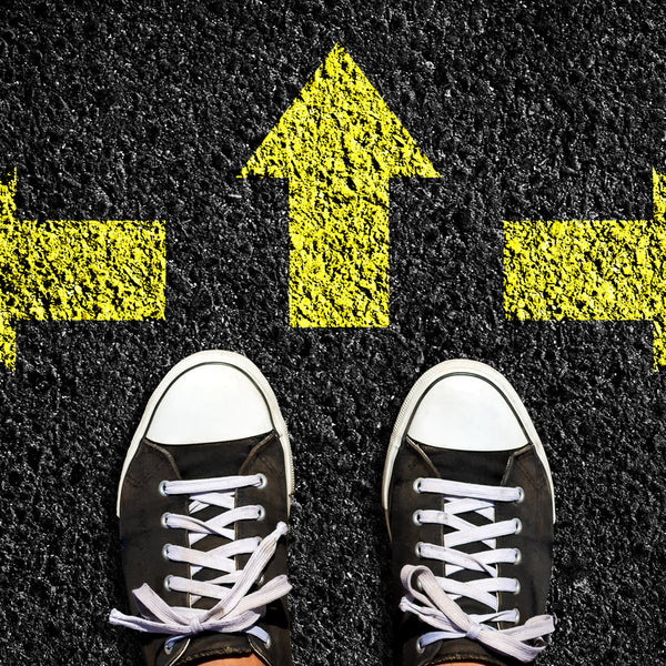 Black sneakers on a black surface with yellow arrows pointing in different directions.