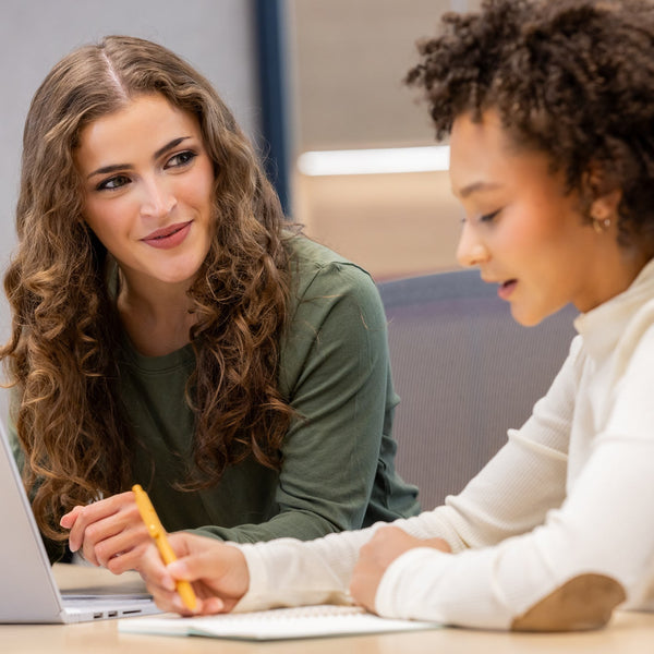 An advisor and student review notes together at a laptop during a one-on-one advising session