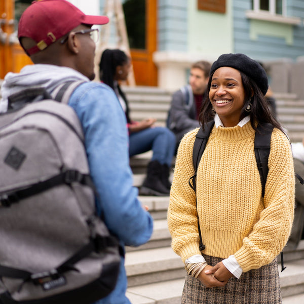 Woman in a yellow sweater standing on steps with people in the background