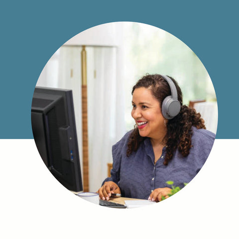 Woman wearing headphones and using a computer with a blue background