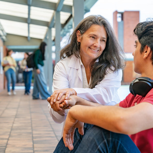 Woman sitting with a young man in a school hallway