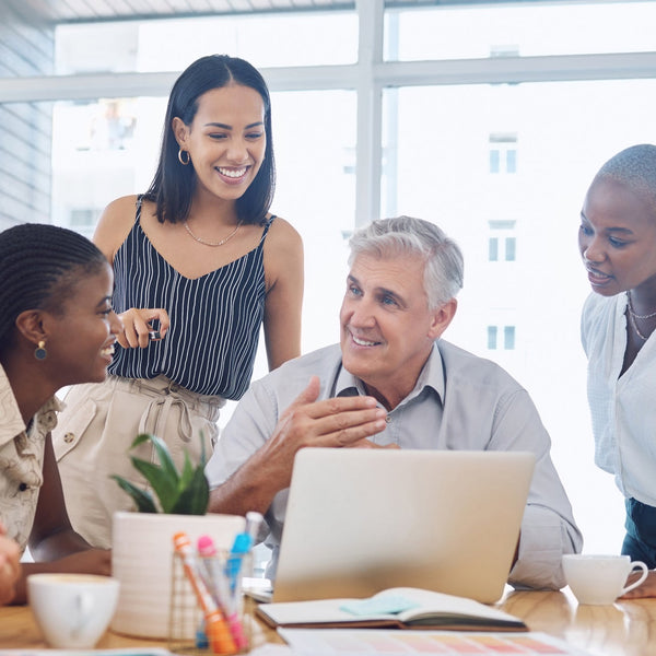 Group of people in a casual meeting around a table with a laptop.