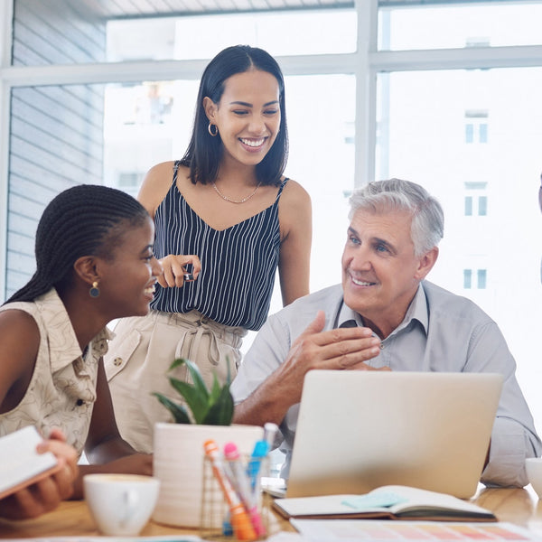 Group of people in a casual meeting around a table with a laptop.