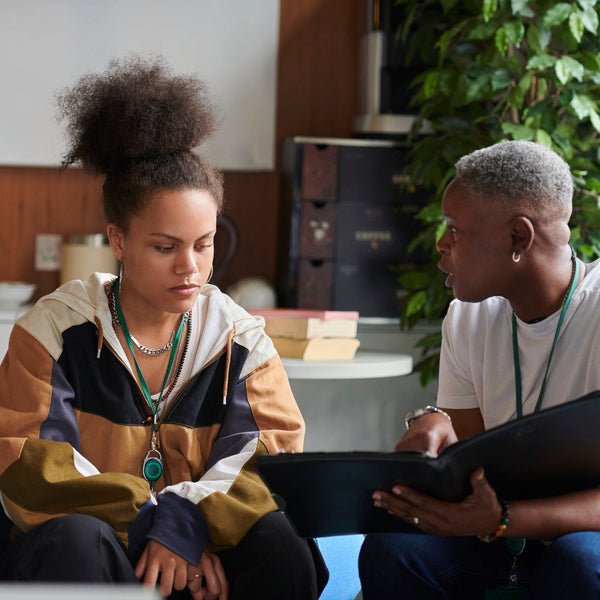 Two people sitting together looking at a tablet in a casual setting.