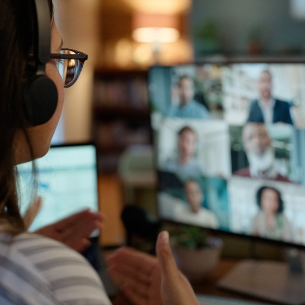 Person wearing headphones participating in a video call with multiple participants on a computer screen.