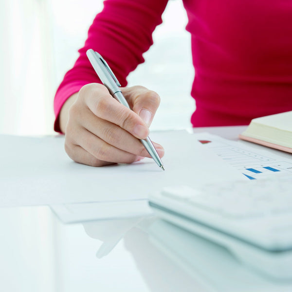Person writing with a pen on a white surface