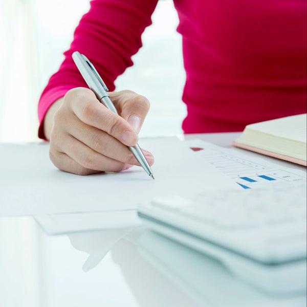 Person writing with a pen on a white surface
