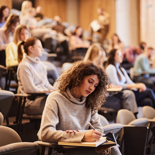 Woman studying in a lecture hall with other students.