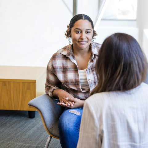 Two women sitting in a room, engaged in conversation.