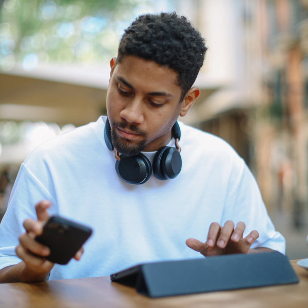 Man using a smartphone and tablet at an outdoor cafe