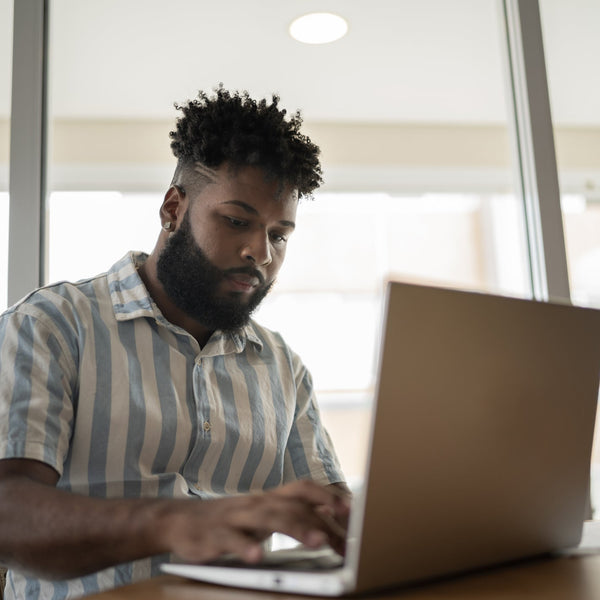 Man using a laptop in a bright room with large windows