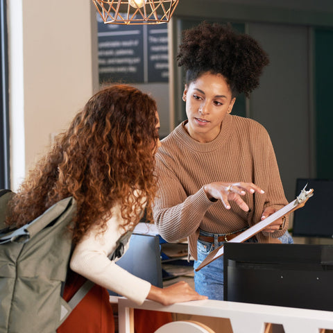 Two women at a reception desk in an office setting