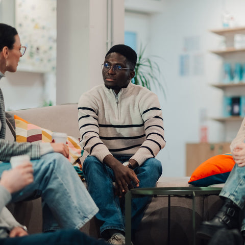 Group of people sitting in a circle in a modern living room setting