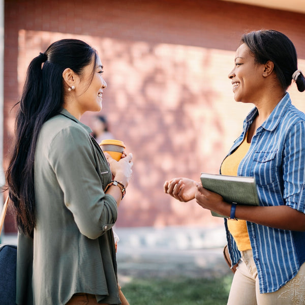 Two women talking outdoors with a building in the background